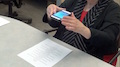 A woman holding an iPhone over a document